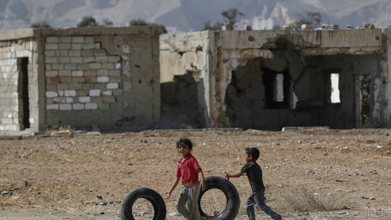 Kinder spielen mit alten Reifen mitten zwischen zerstörten Häusern in der syrischen Stadt Douma. 