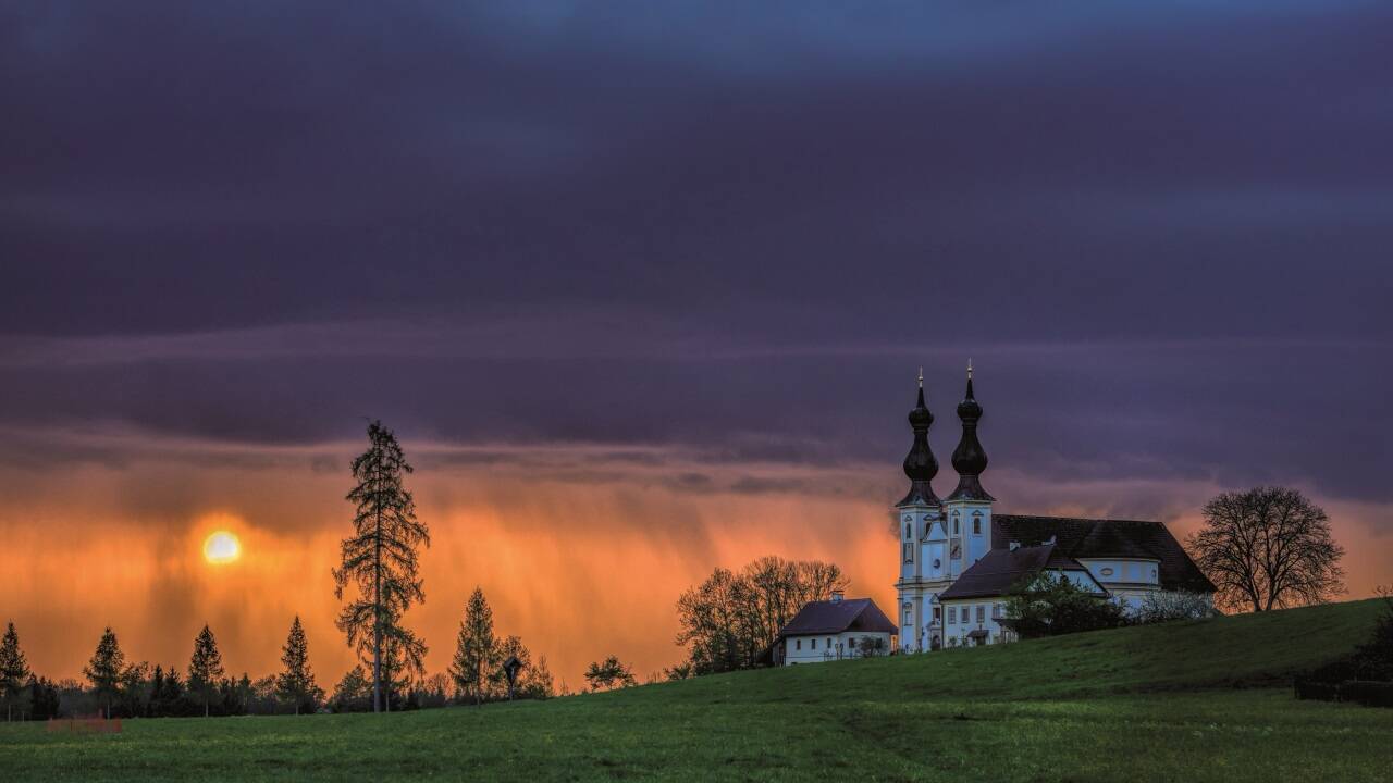 Maria Bühel bei Oberndorf bei Gewitterstimmung beim Sonnenuntergang. 