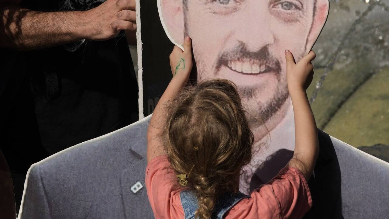 Ein Mädchen berührt bei einer Demonstration in Jerusalem das Gesicht einer Geisel auf Karton.  