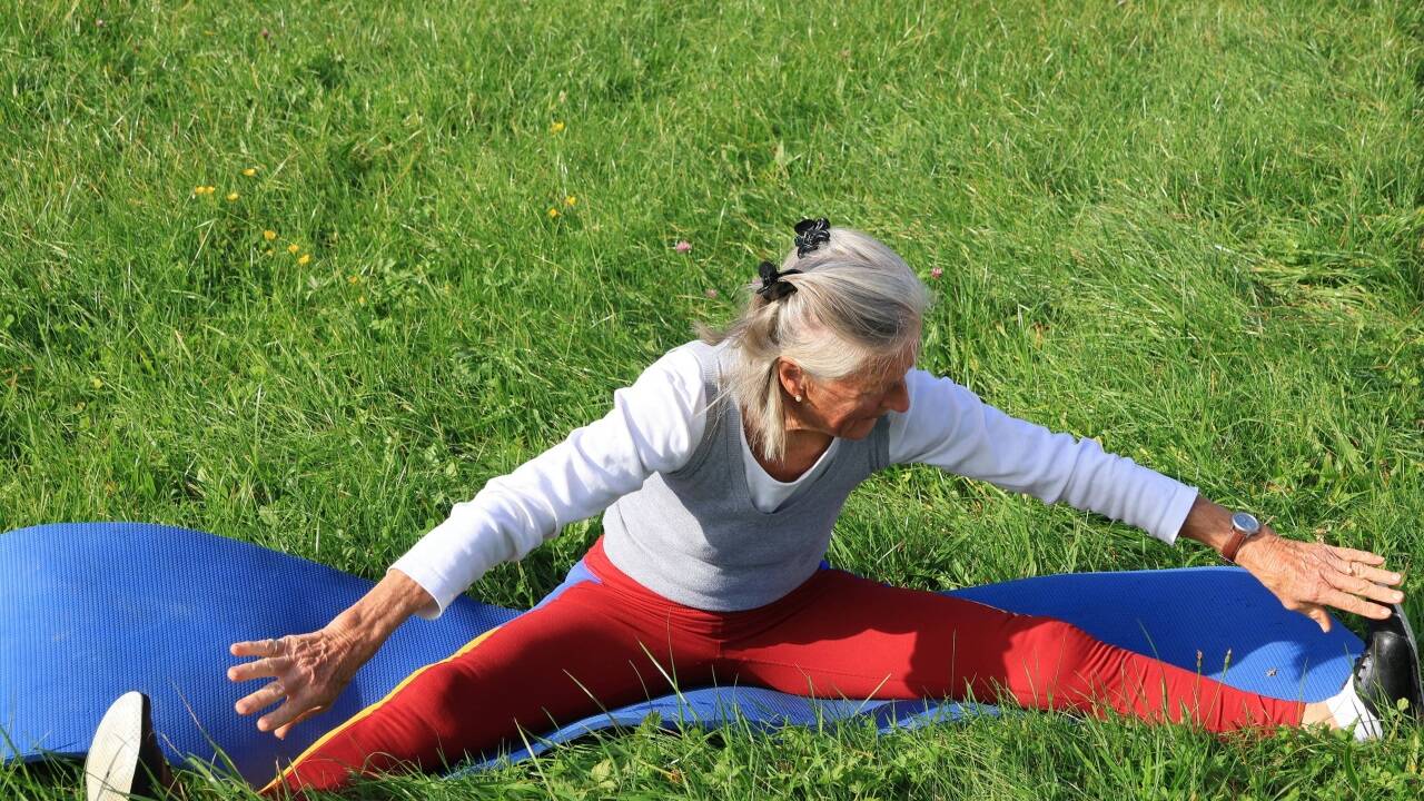 Helga Lasshofer turnt in der Wiese vor ihrem Haus in Niederalm. 