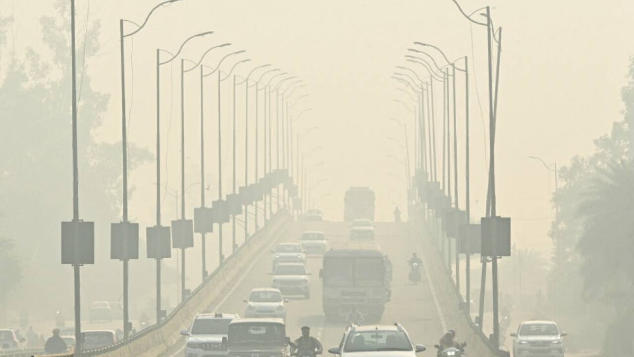 Verkehrsteilnehmer auf einer Straße im Smog in Amritsar 