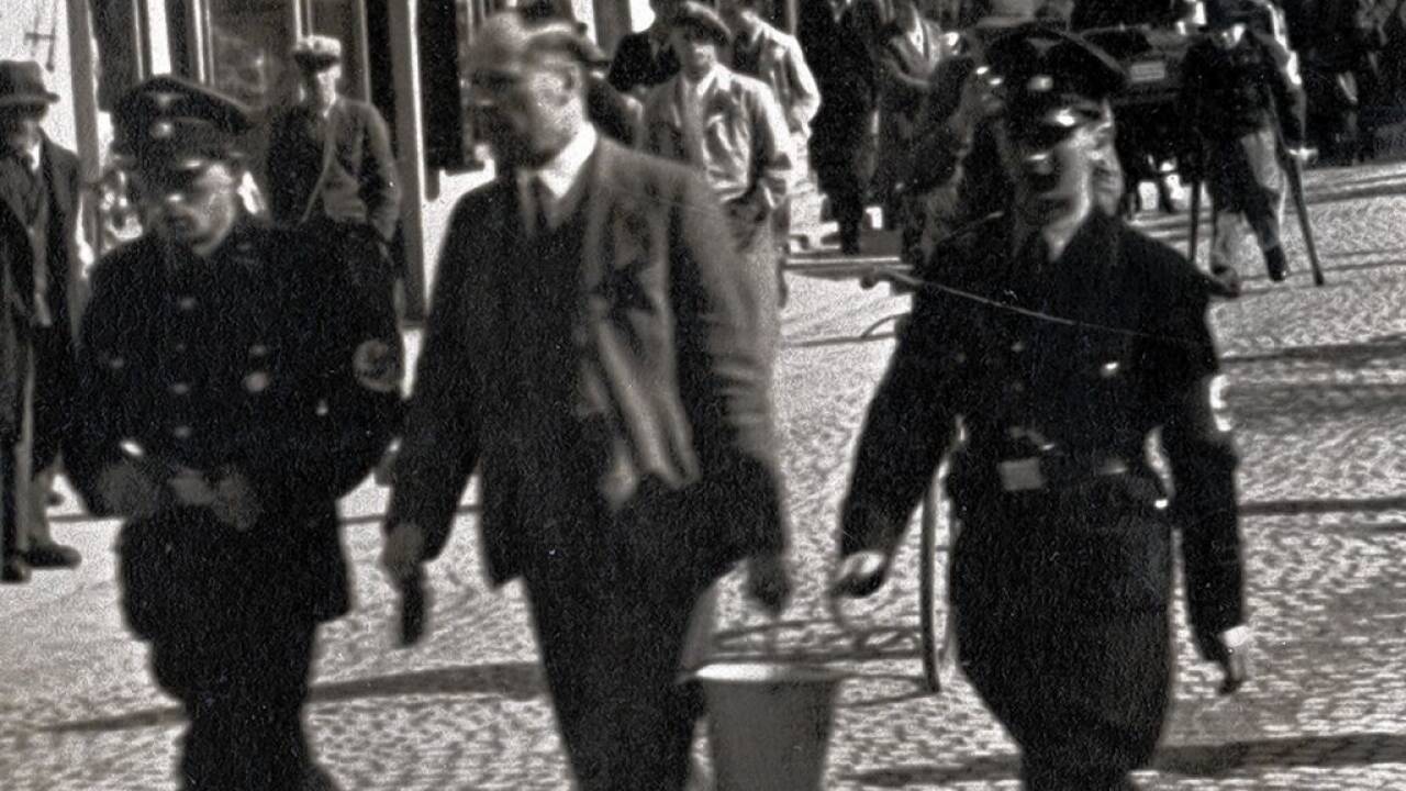 Der Bezirkshauptmann Rudolf Dworzak, ein Christlich-Sozialer, wird gleich nach dem Anschluss abgeführt und muss Ständestaat-Parolen wegputzen. 