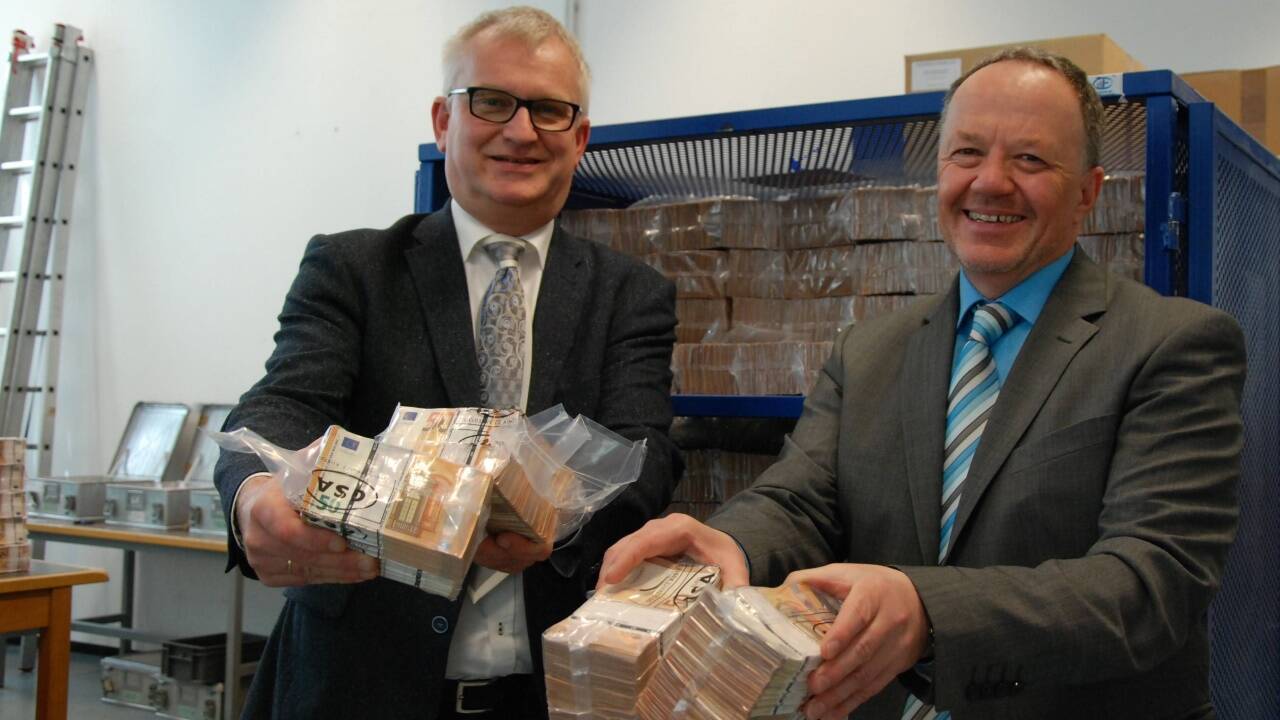 Landesdirektor Michael Lanik (links) und sein Stellvertreter Erich Karner mit vier Notenbündeln 50er – umgerechnet rund 200.000 Euro. Ist die Palette dahinter voll, liegen hier rund 33 Millionen Euro cash.                              Bilder:  