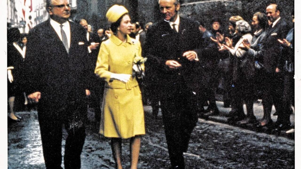 Die Queen im sonnengelben Gewand beim Altstadtspaziergang im regennassen Salzburg, an ihrer Seite der damalige Landeshauptmann Hans Lechner und Stadtverkehrsdirektor Heinz Rennau.  