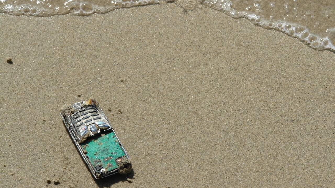 Mit dem Handy am Strand ... Das kann für das Gerät Folgen haben – aber vor allem für die Geldbörse. 