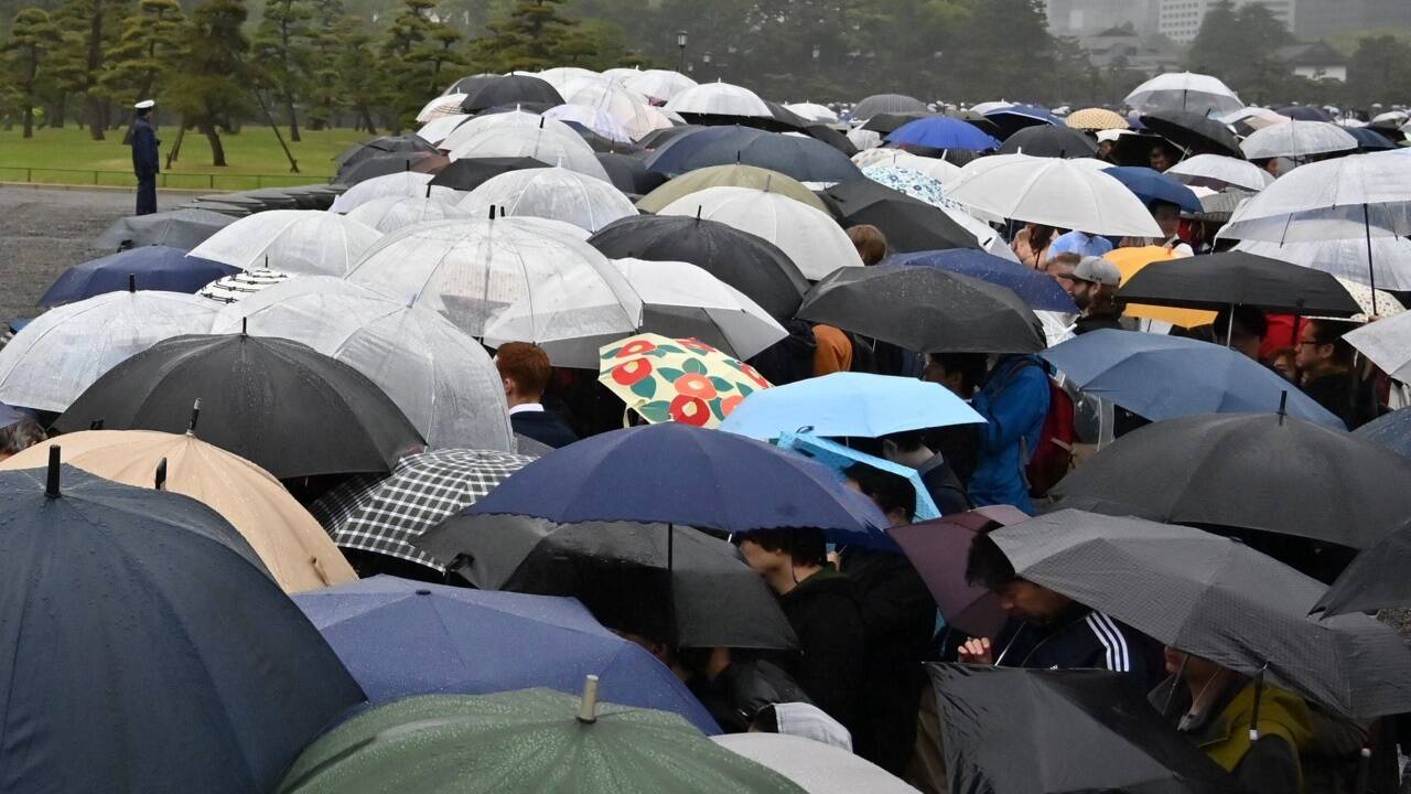 Die Öffentlichkeit war von der Zeremonie zwar ausgeschlossen, viele Japaner kamen aber dennoch in der Nähe des Kaiserpalasts zusammen. Das Wetter präsentierte sich allerdings wie hierzulande von seiner nassen Seite. 