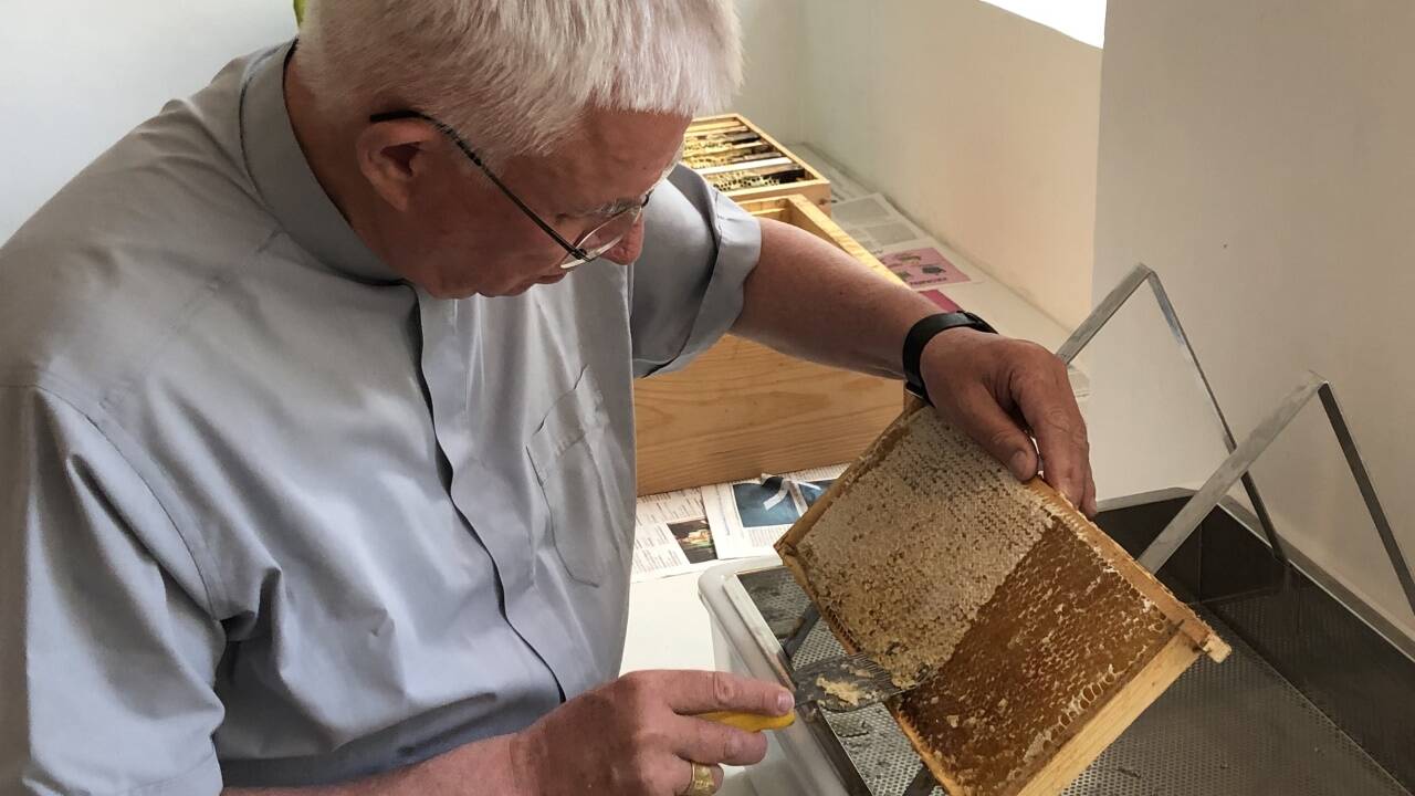 Der Erzbischof entdeckelt die Waben.  