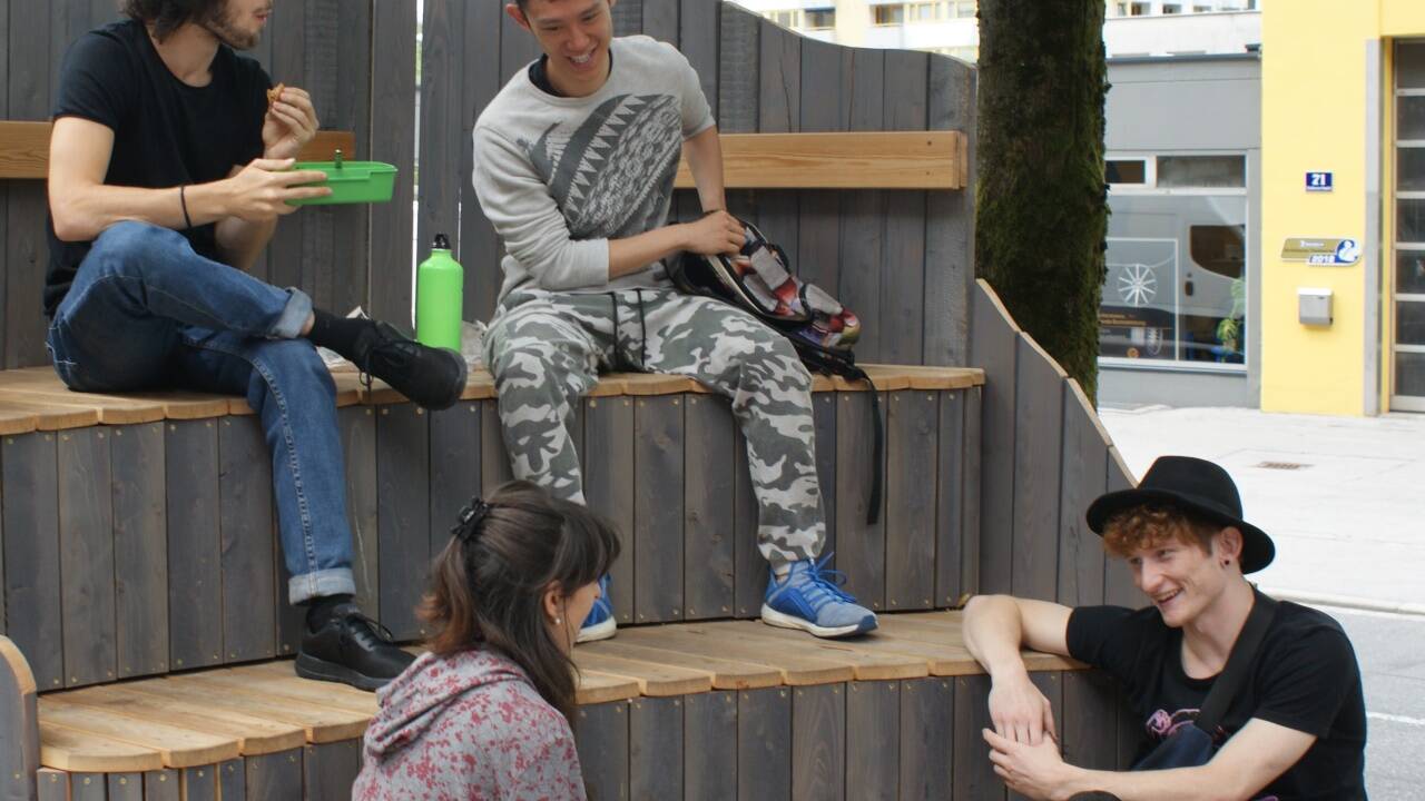 Die vier Tänzer nutzen die Sitzmöglichkeit vor der Tanzakademie „SEAD“ zum gemütlichen Beisammensein. 
