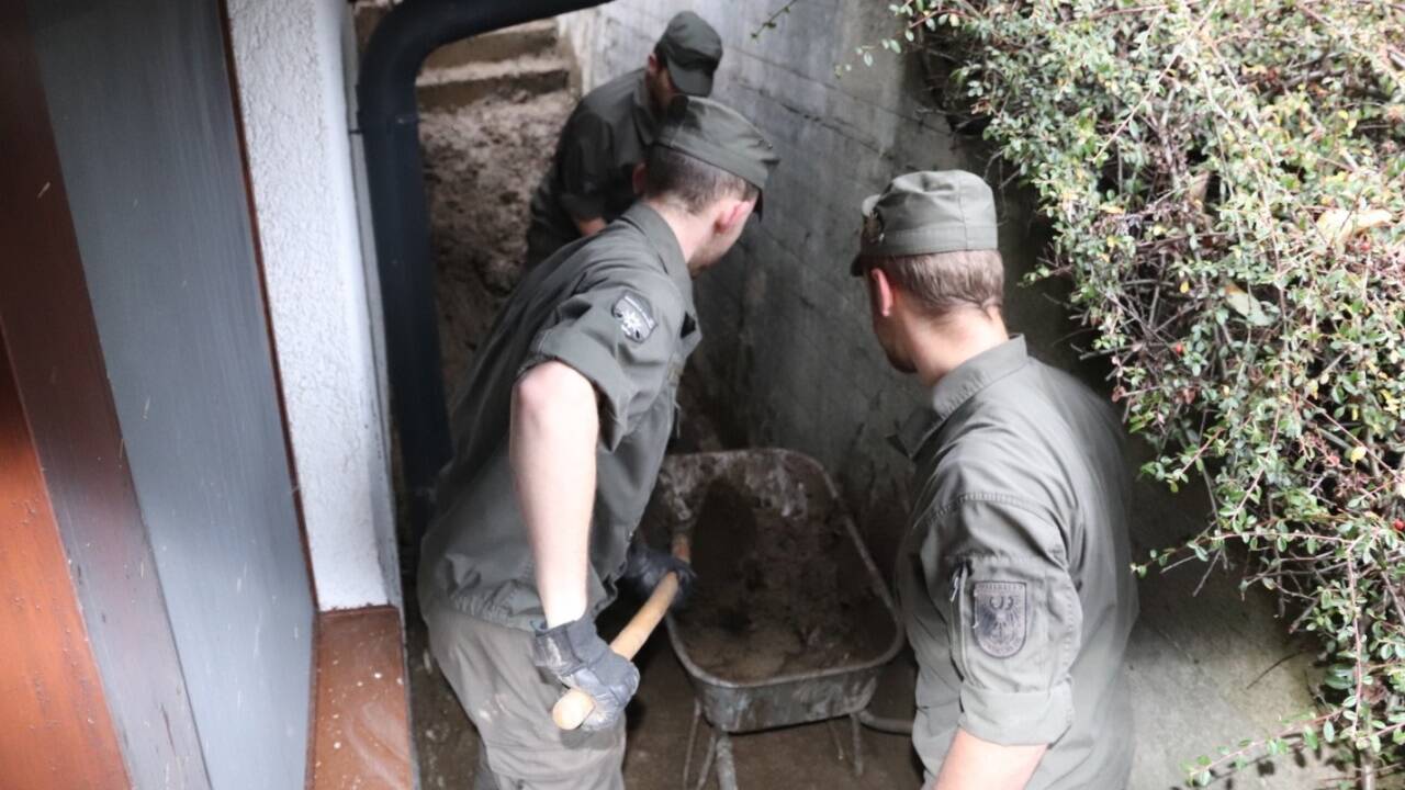 Mit Schaufel und Schubkarre befreien die Soldaten die Außenbereiche der Häuser von Schlamm. 