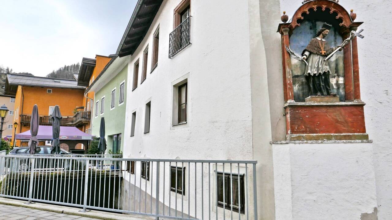 Zu erkennen ist der heilige Nepomuk am Priestergewand. In der einen Hand hält er das Kreuz, in der anderen die Märtyrerpalme.  