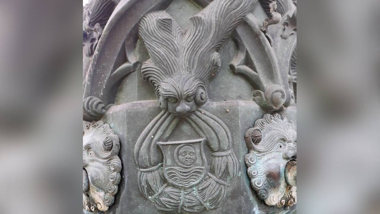 Mischwesen mit geweihartigem Kopfputz halten das Wappen des Stifts Mondsee, den gesichtigen Vollmond mit der eingeschriebenen Sichel und dem See.  
