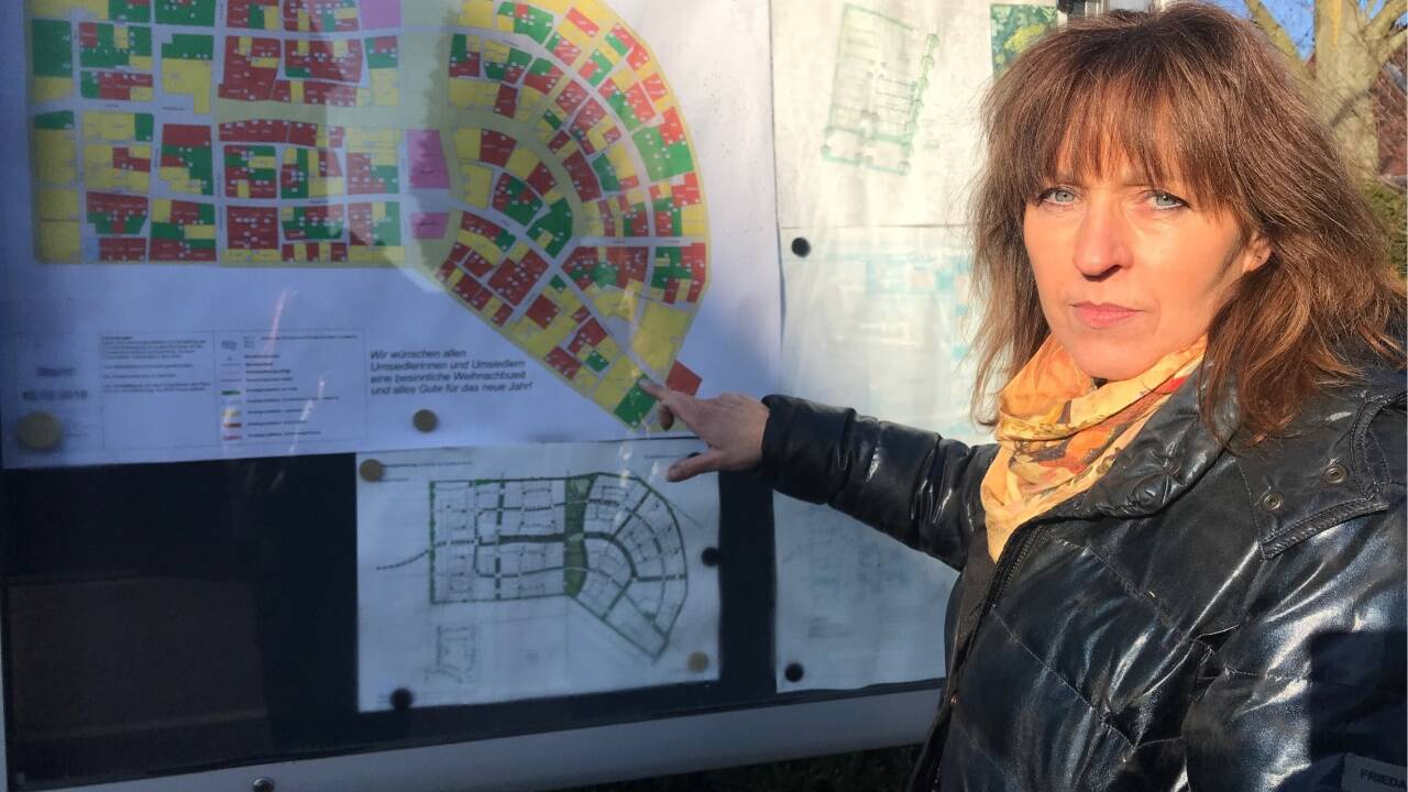 In Kuckum hängt in einem Schaukasten der Plan der neuen Ansiedlung. Marita Dresen zeigt, wo sie hinziehen soll. 