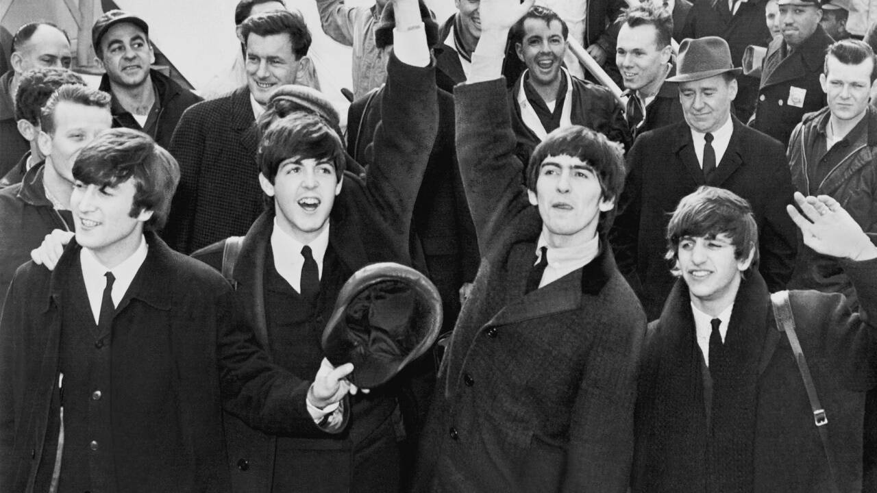 1964: Tausende Fans bereiten den Beatles in New York (hier bei der Ankunft) einen begeisterten Empfang, der den Kennedy-Flughafen für nahezu fünf Stunden lahmlegt. 