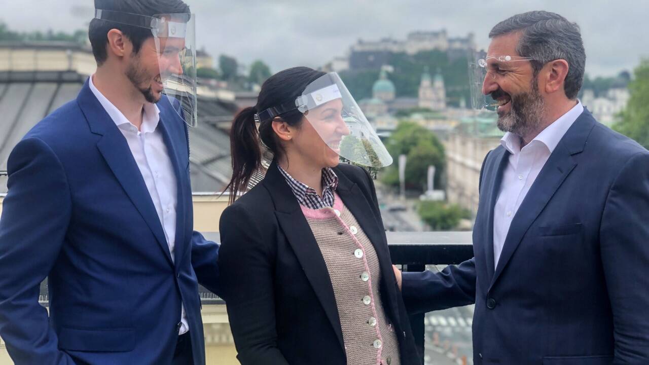 Unternehmer Georg Imlauer mit seinen Kindern (und Mitarbeitern) Thomas – er ist Gastronomieleiter – und Lisa Imlauer – sie ist Assistentinder Geschäftsleitung – auf der Dachterrasse seines Hotels in Salzburg. So wie alle Mitarbeiter im Service sind auch sie mit Gesichtsvisiren ausgestattet. 