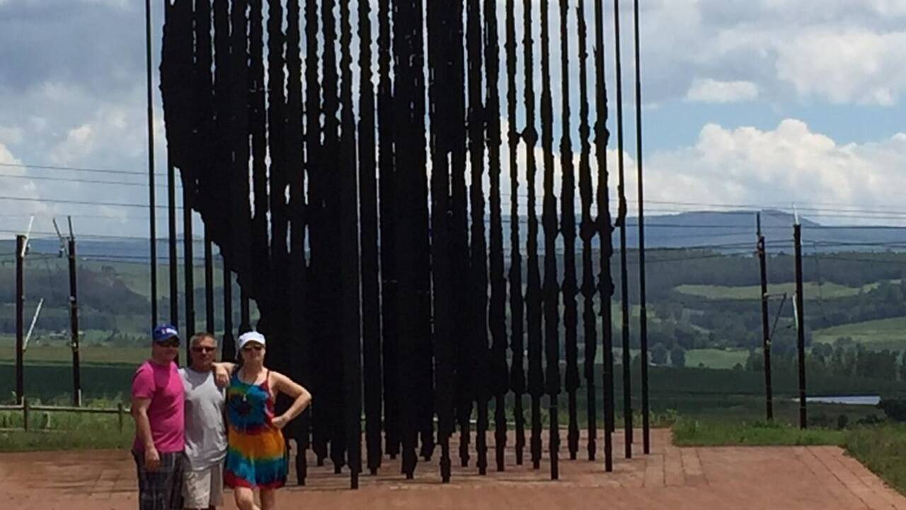 Tommy und Sylvia Neumeister mit ihrem Vater „Edi“ (Mitte) vor einem Nelson-Mandela-Denkmal in der Nähe von Howick, wo das Mordopfer lebte. 