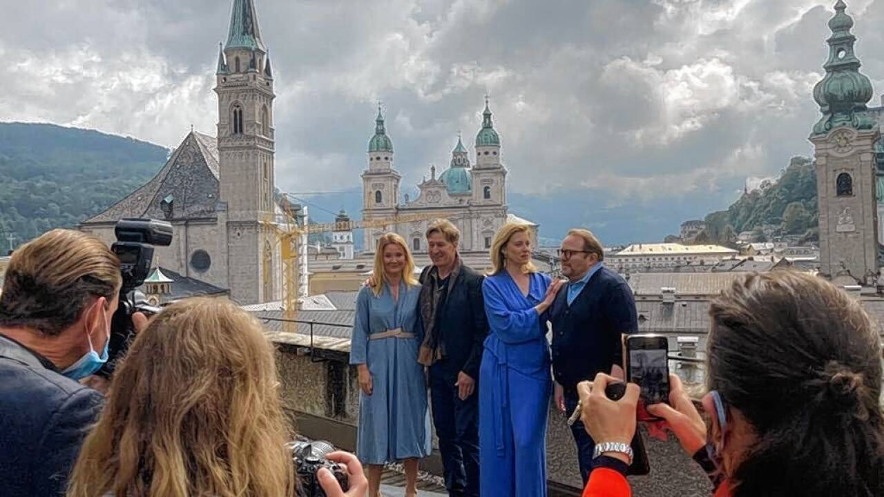 Einige Schauspieler aus dem „Jedermann“-Team setzen sich für die Fotografen vor der Domplatz-Kulisse in Pose.  