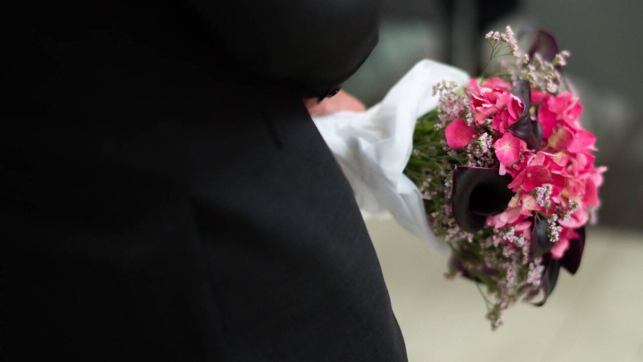 Einige der Trauergäste haben Blumen mitgebracht.  