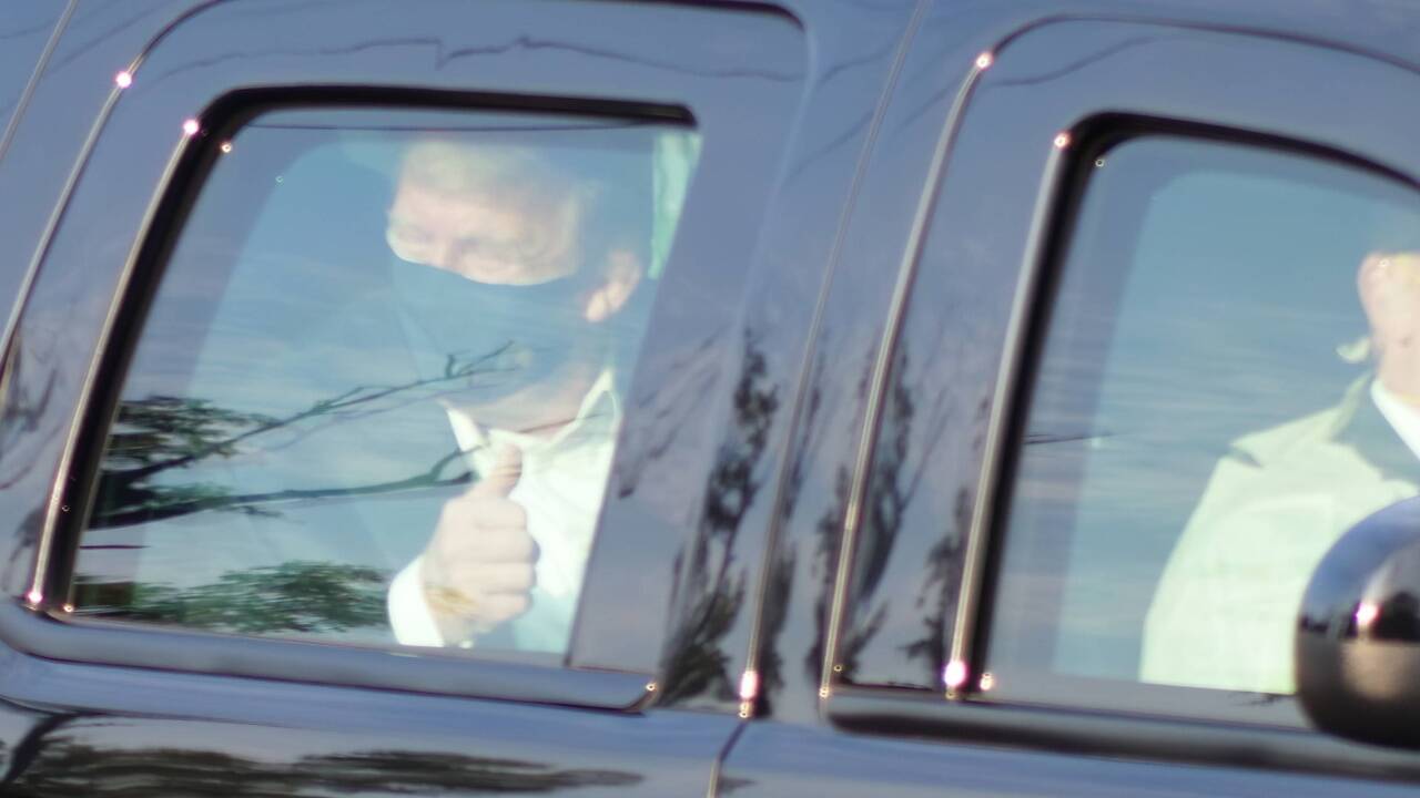 Hinter Panzerglas: Donald Trump trägt Maske und winkt seinen Fans zu. 