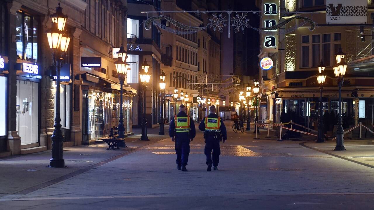 Polizisten kontrollieren die Ausgangssperren in einer Einkaufsstraße in Budapest. Polizisten kontrollieren die Ausgangssperren in einer Einkaufsstraße in Budapest.