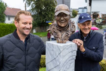 Niki Laudas Sohn Lukas und die deutsche Rennfahrerlegende Hans-Joachim Stuck freuen sich über die Enthüllung der Büste.  