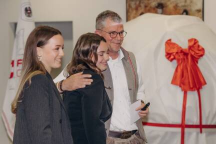 Firmenchef Gerald Heerdegen mit seinen Töchtern Anna und Emma.Im Hintergrund sind das hier noch verhüllte „Geschenk an die Region“ sowie die neuen Unternehmensfahne zu sehen.  