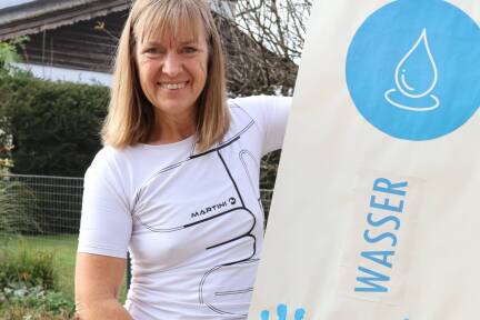 Obfrau Gerti Höller vom Kneipp-Aktiv-Club Thalgau mit einer Fahne, die von den Kindern der Nachmittagsbetreuung für das Jubiläum gestaltet wurden. Wasser ist eine der fünf Säulen der kneippschen Gesundheitslehre. 