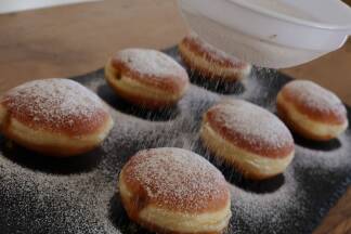 Zum Abschluss kommt Staubzucker auf die Krapfen. 