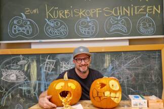 Rainer Likar leitete das Kürbisschnitzen. Auf der Tafel im Hintergrund skizzierte er für die Teilnehmenden ein paar Vorlagen zur Inspiration. 