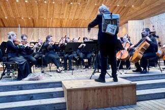 Das sieht man auch nicht jeden Tag: Dirigent Reinhold Wieser ließ es sich nicht nehmen, bei den Zugabe-Stücken den Rucksack, den er nach dem offiziellen Konzertende von der Trachtenmusikkapelle Bramberg überreicht bekam, zu tragen. Bilder:  Christa Nothdurfter Im Bild mit einem Teeil des Orchesters.  