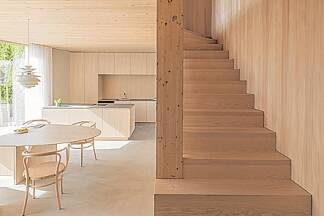 Eine schlichte, gewendelte Holztreppe an der Ostwand führt nach oben. Auf ein Geländer wurde verzichtet. Den Sicht- und Absturzschutz bilden Holzstützen, welche die Decke tragen. 