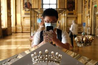Ein Besucher macht im Apollon-Saal des Louvre ein Foto von zwei Schmuckstücken: dem großen Brustschmuck („Grand nœud de corsage“) und der Krone der Kaiserin Eugénie. Ein Besucher macht im Apollon-Saal des Louvre ein Foto von zwei Schmuckstücken: dem großen Brustschmuck („Grand nœud de corsage“) und der Krone der Kaiserin Eugénie.
