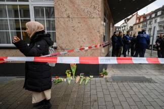Eine Passantin am Tatort in Hanau, an dem die Polizei Absperrbänder angebracht hat.  Eine Passantin am Tatort in Hanau, an dem die Polizei Absperrbänder angebracht hat.