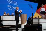 IOC-Präsident Bach hält den Entschluss hoch 