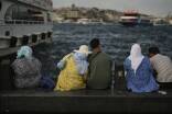 Menschen sitzen am Ufer des Bosporus in Istanbul. 
