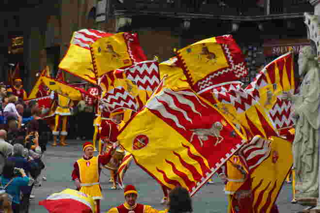 Fahnenschwinger ziehen durch die Straßen von Siena